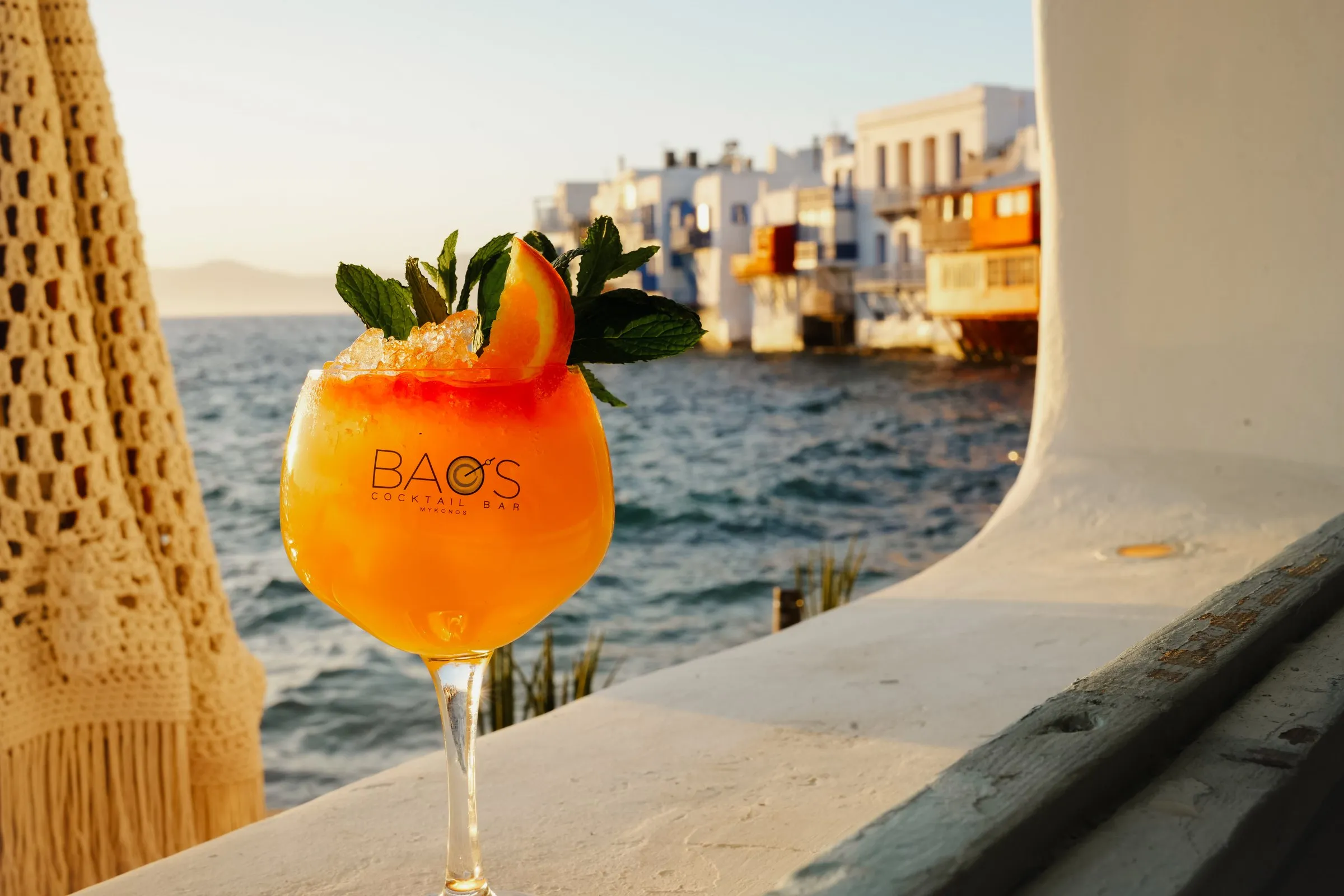 A BAO'S cocktail on the ledge beneath a macramé parasol, the houses of Little Venice behind
