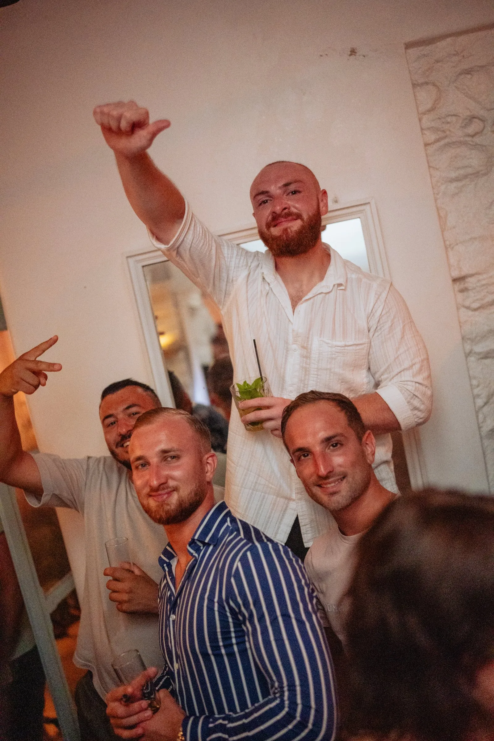 A group of friends celebrating with their drinks and arms raised at BAO'S