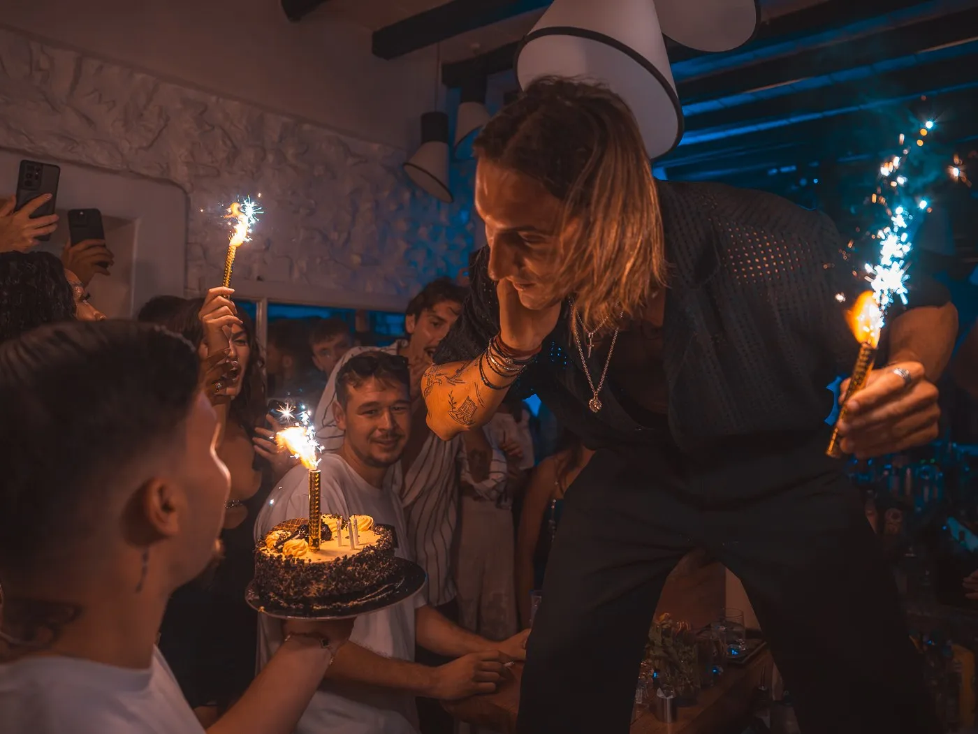 A cake carried out through the crowd at BAO'S, sparklers burning on top