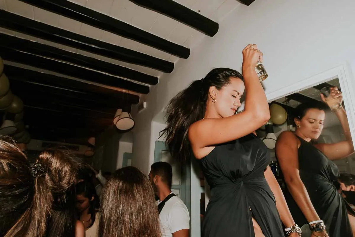 A guest dancing with her arm raised in a crowded room at BAO'S at night