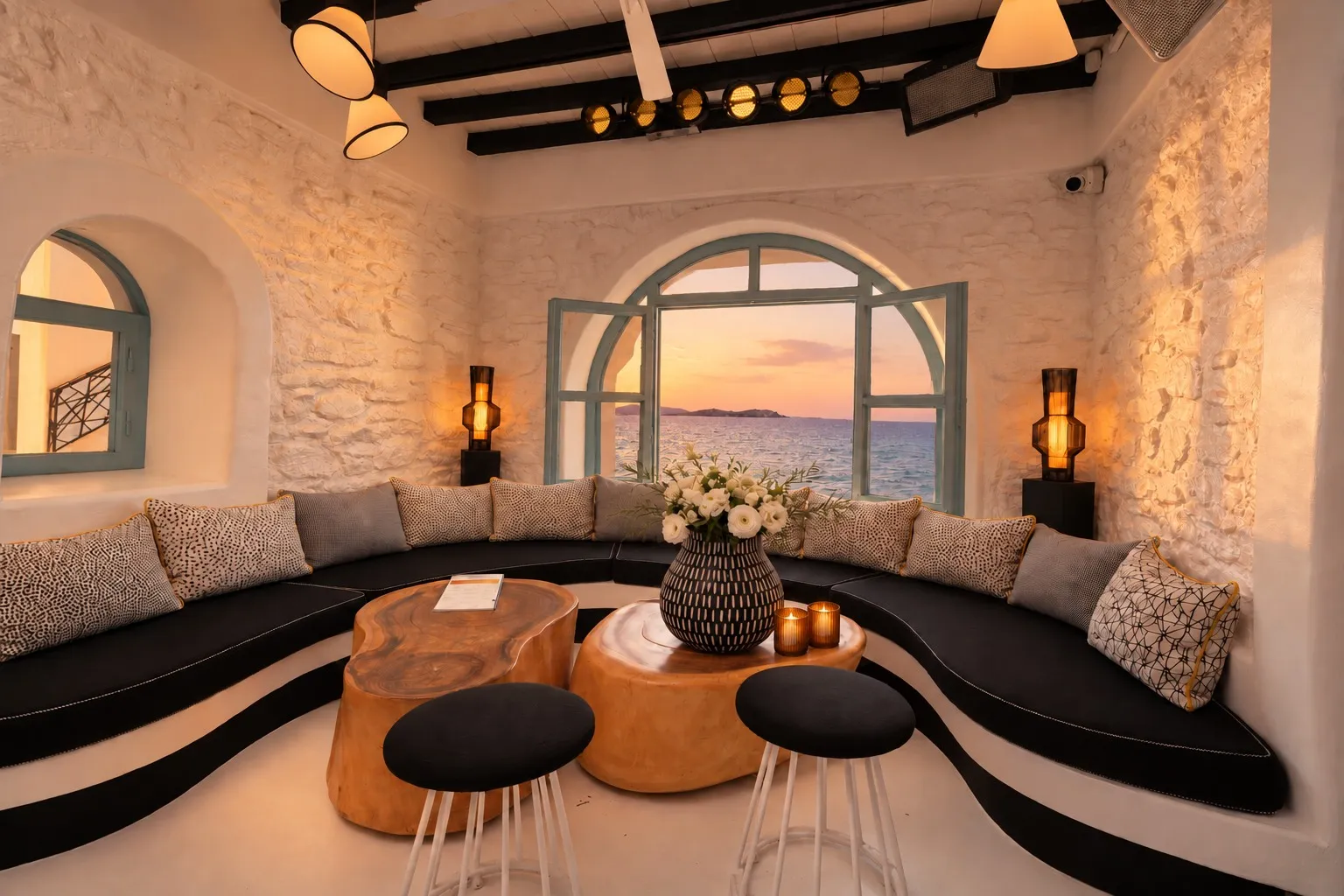 The Rotonda Table at BAO'S in warm evening light, facing the open arched window and the sea