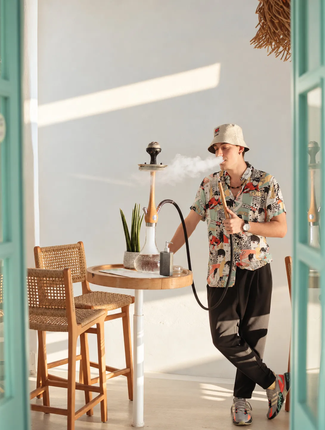 A guest standing beside the shisha at BAO'S, breathing out smoke in the afternoon light