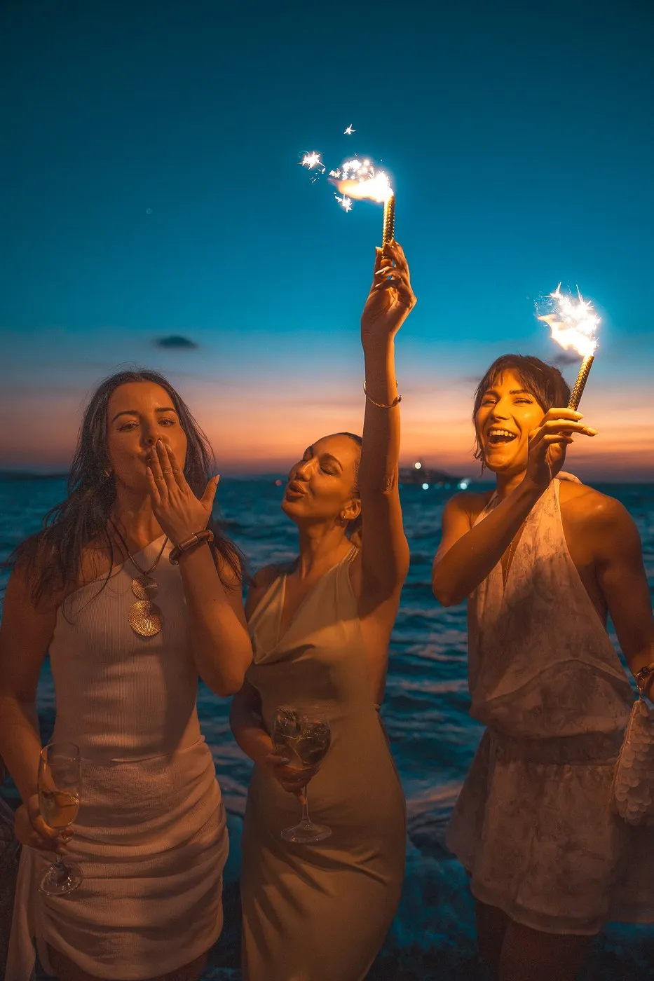 Guests with sparklers against the sunset over the sea at BAO'S