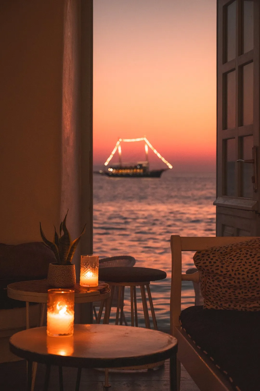 The Rotonda Table at BAO'S in warm evening light, facing the open arched window and the sea