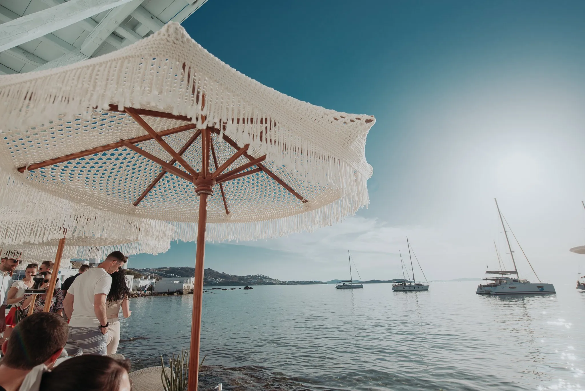 Macramé parasols over the seafront tables at BAO'S, with boats moored on the bay beyond