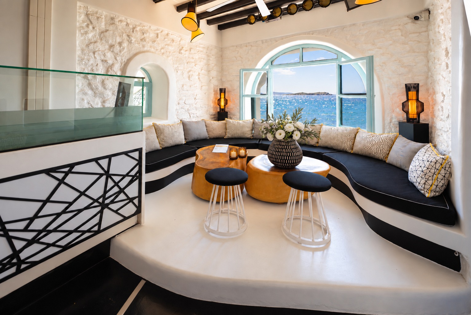 The Rotonda Table seen from the walkway railing in daylight, raised on its white platform beside the arched window to the sea