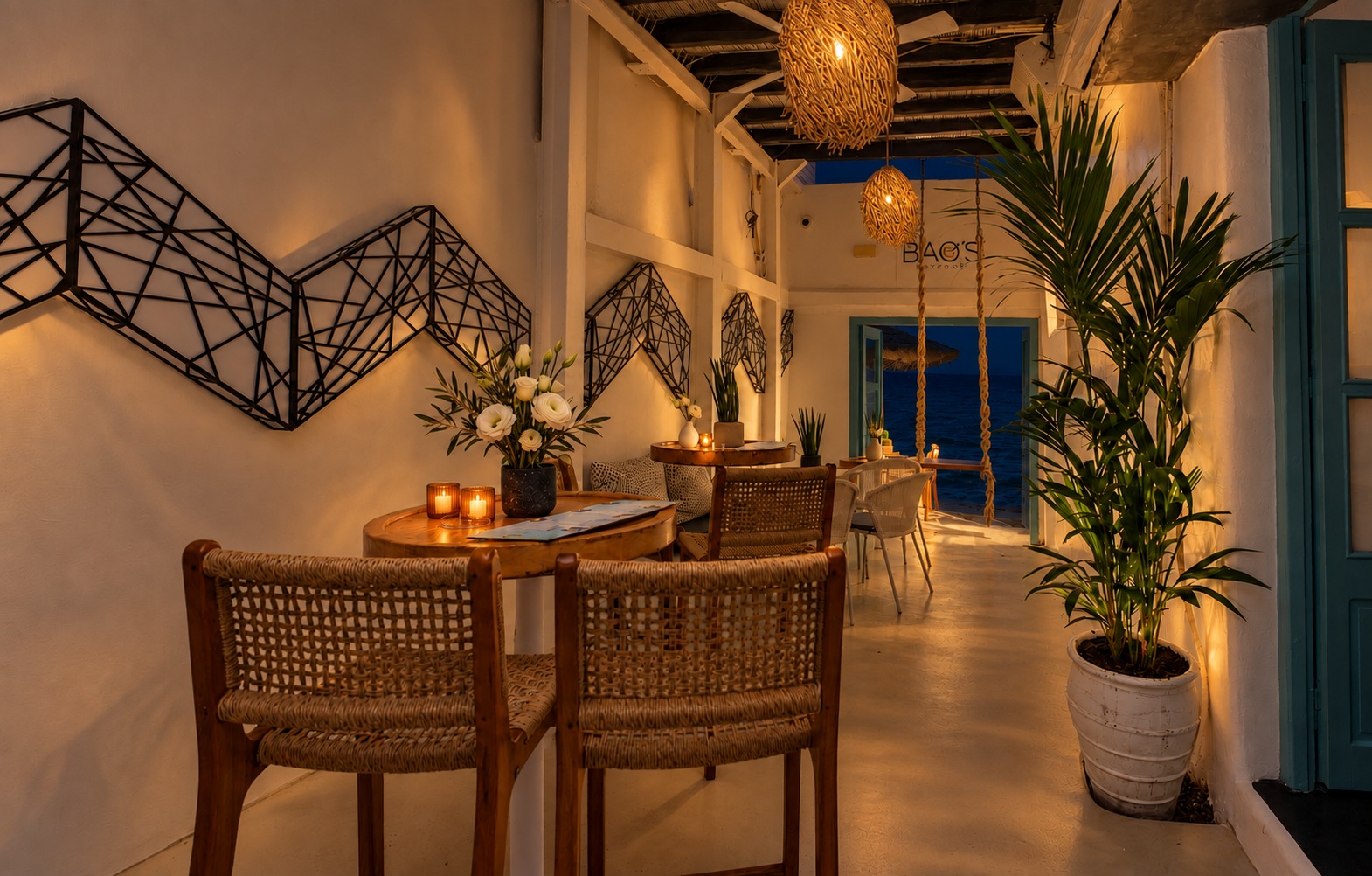 The same walkway at night, lit by lanterns and candles, the doorway at the end a deep blue