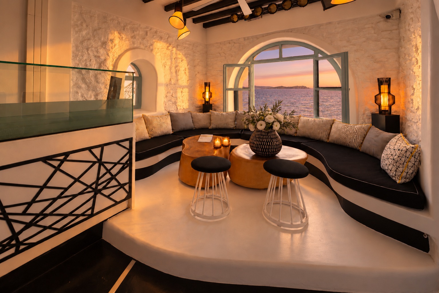 The Rotonda Table seen from the walkway railing at sunset, candles on the tables and warm light across the stone wall